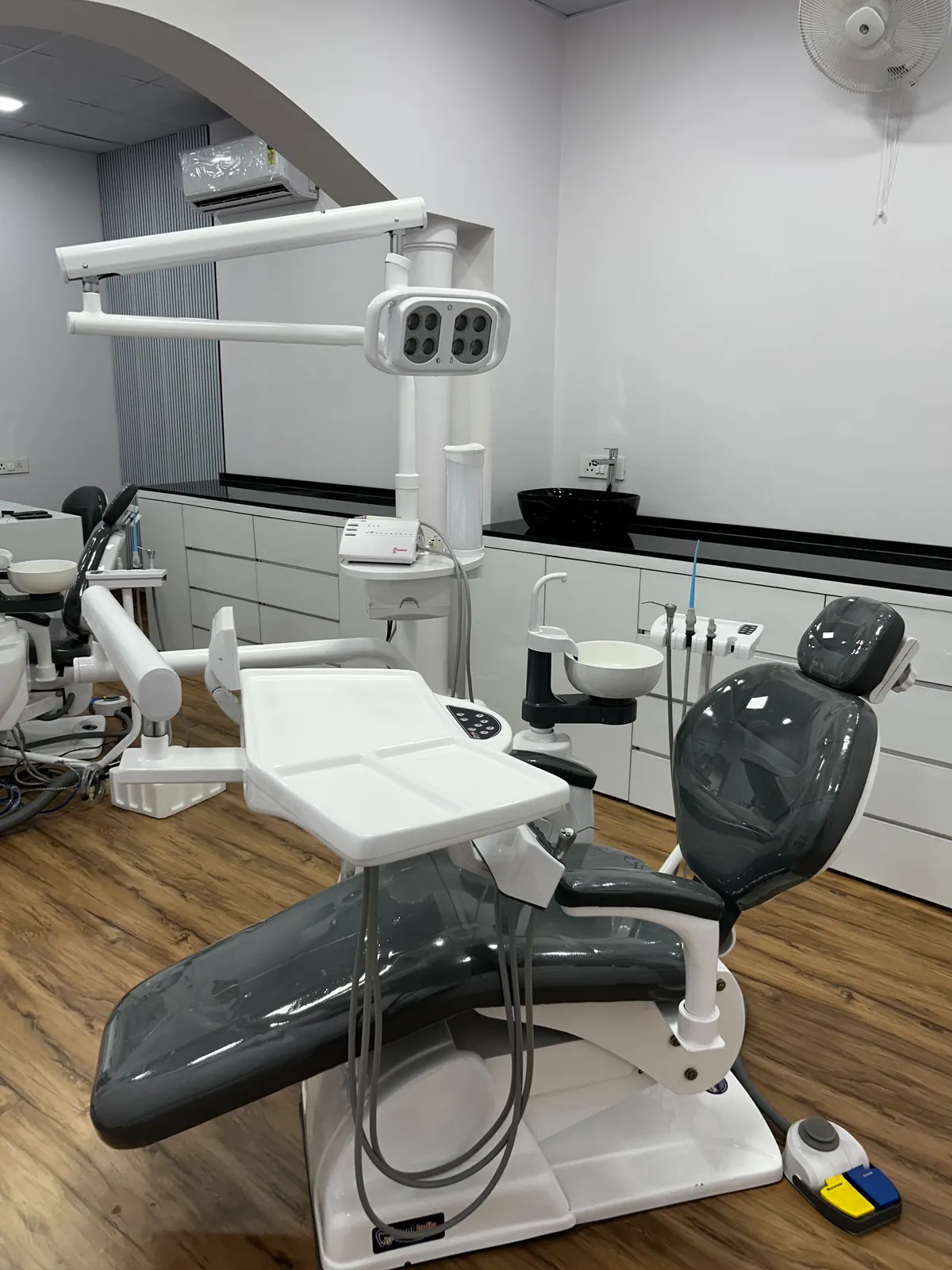 Dental operatory at The Bhatia Dental & Implant Studio with treatment chair, overhead surgical light and chairside delivery unit